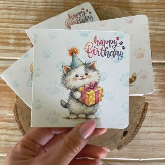 Biglietto di compleanno in carta piantabile con gattino e regalo, tenuto in mano