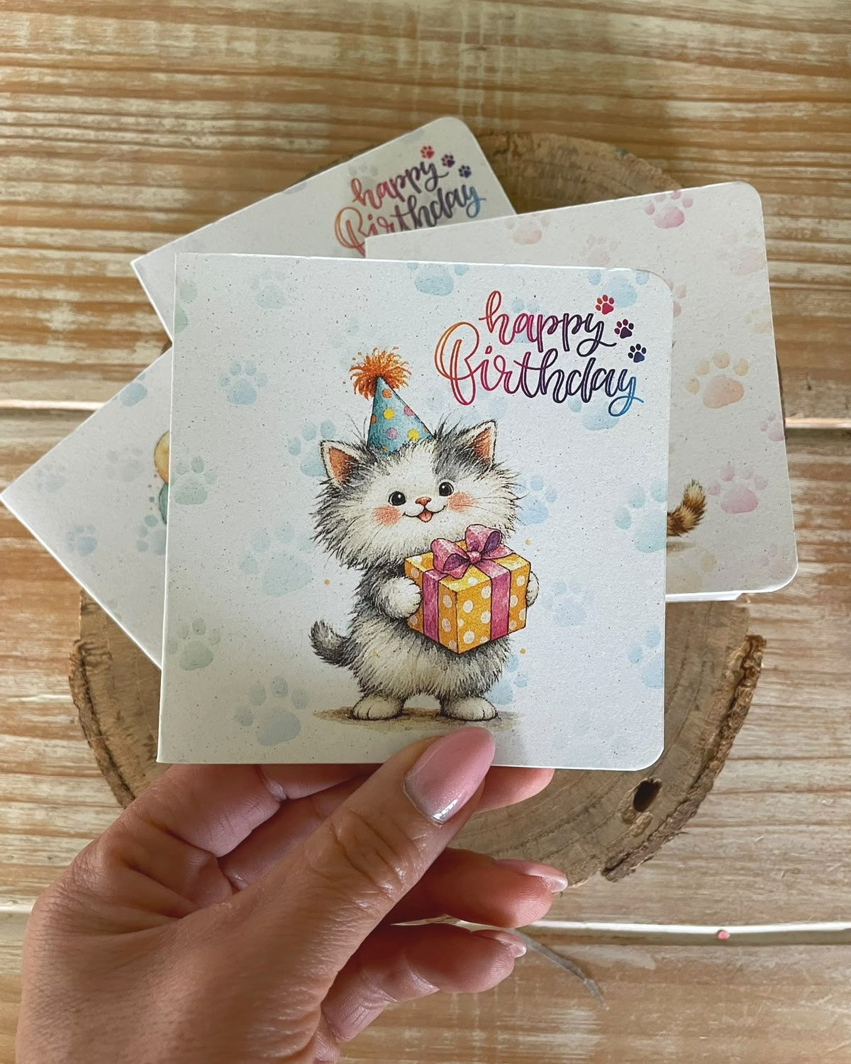 Biglietto di compleanno in carta piantabile con gattino e regalo, tenuto in mano